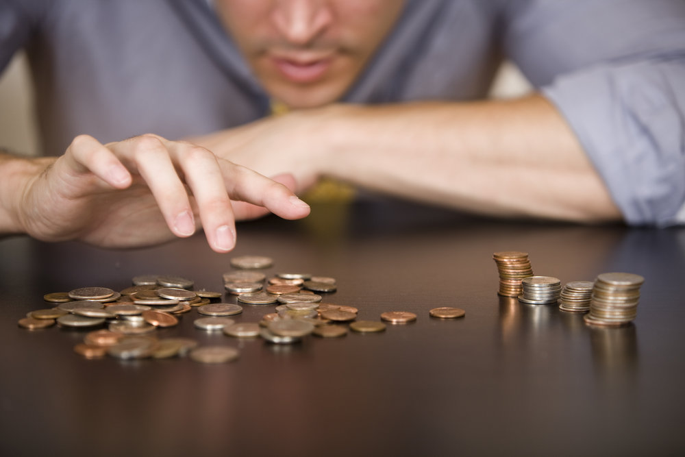 A man counts his coins on a tabletop.