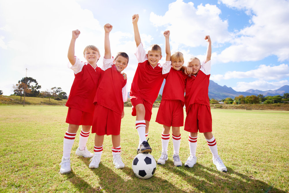 A young soccer team looking at the camera while cheering