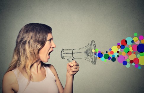 Portrait angry screaming young woman holding megaphone isolated on grey wall background. Negative face expression emotion feelings. Propaganda, breaking news, power, social media communication concept