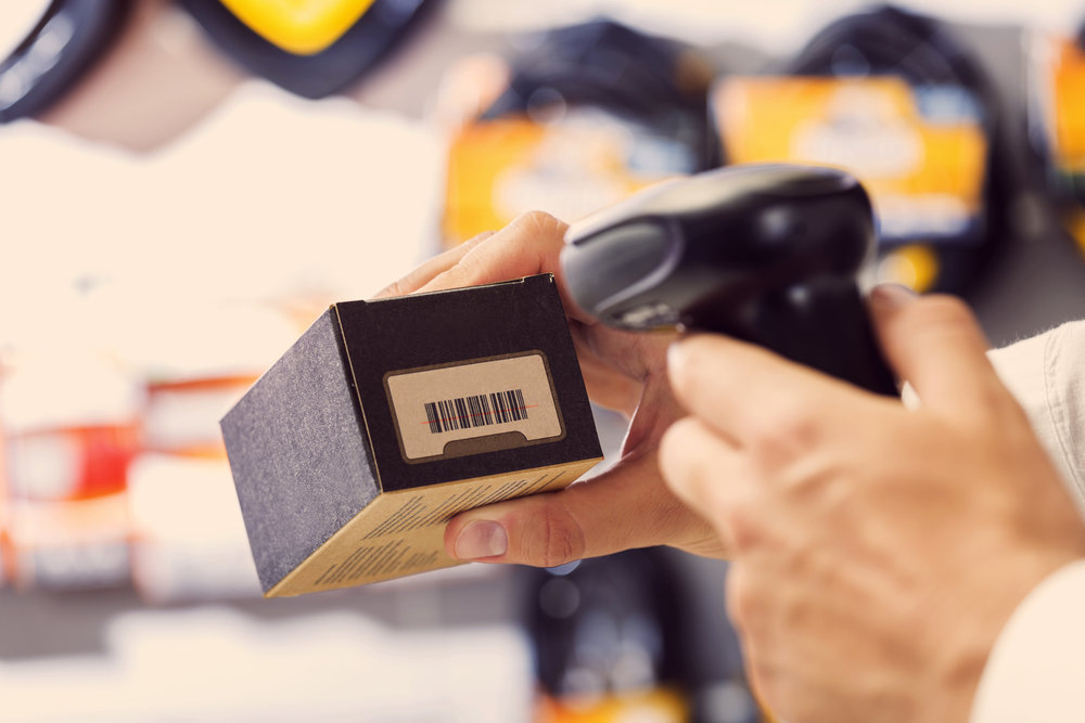 Shop assistant scanning a bar code using manual reader. Focus on hands.