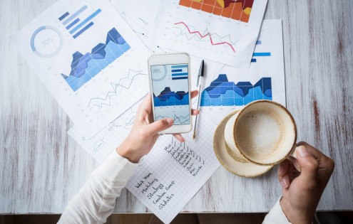 Business manager doing the books at a restaurant using a smart phone and having a cup of coffee