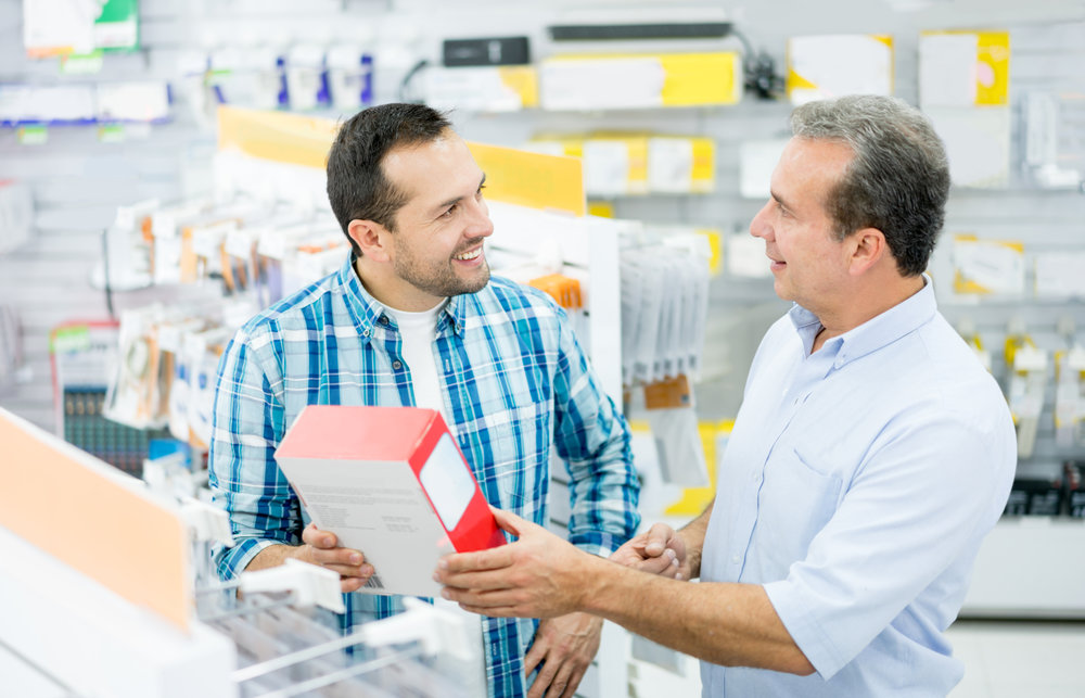 Casual man shopping at an electronics store and talking to salesman