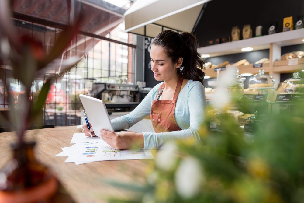 Happy Latin American business woman doing the books at a restaurant