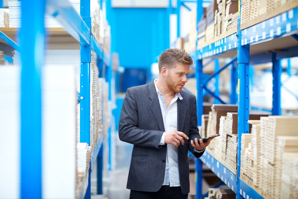 Young businessman in warehouse checking goods on racks