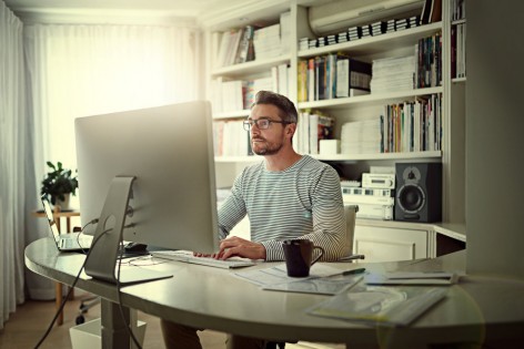 Cropped shot of a man sitting behind his computer in his home office