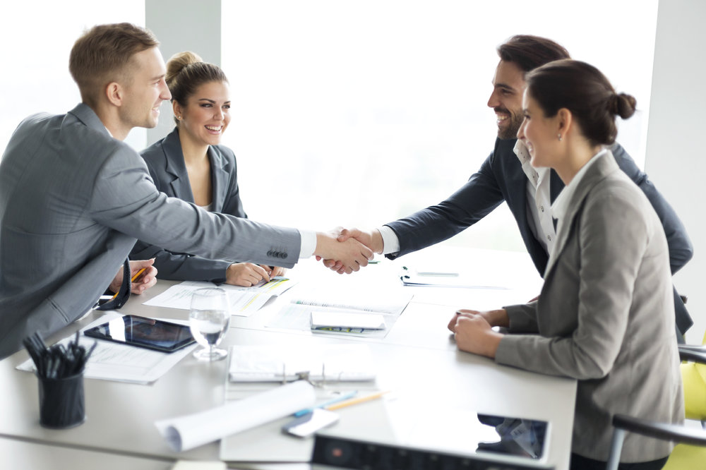 Happy couple meeting their financial advisor, shaking hands